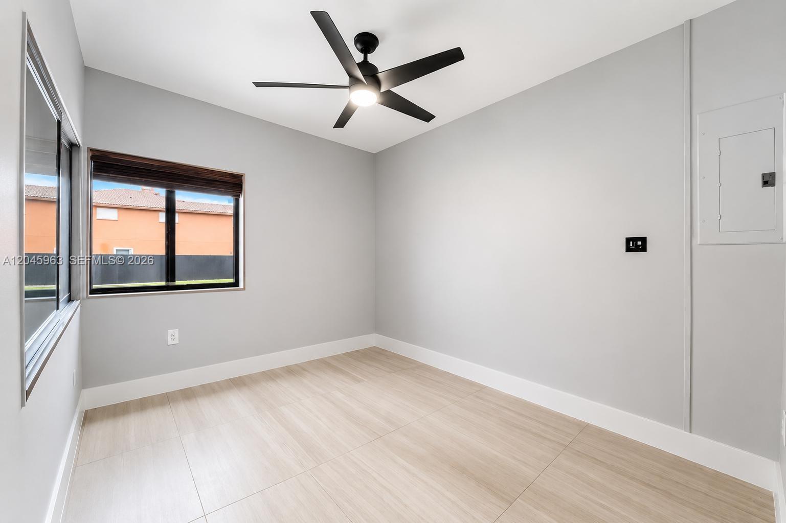 An empty room features light gray walls, wood-look tile flooring, a ceiling fan, and a window — 14888 SW 140th St # 1, Miami FL 33196, MIAMI, FL