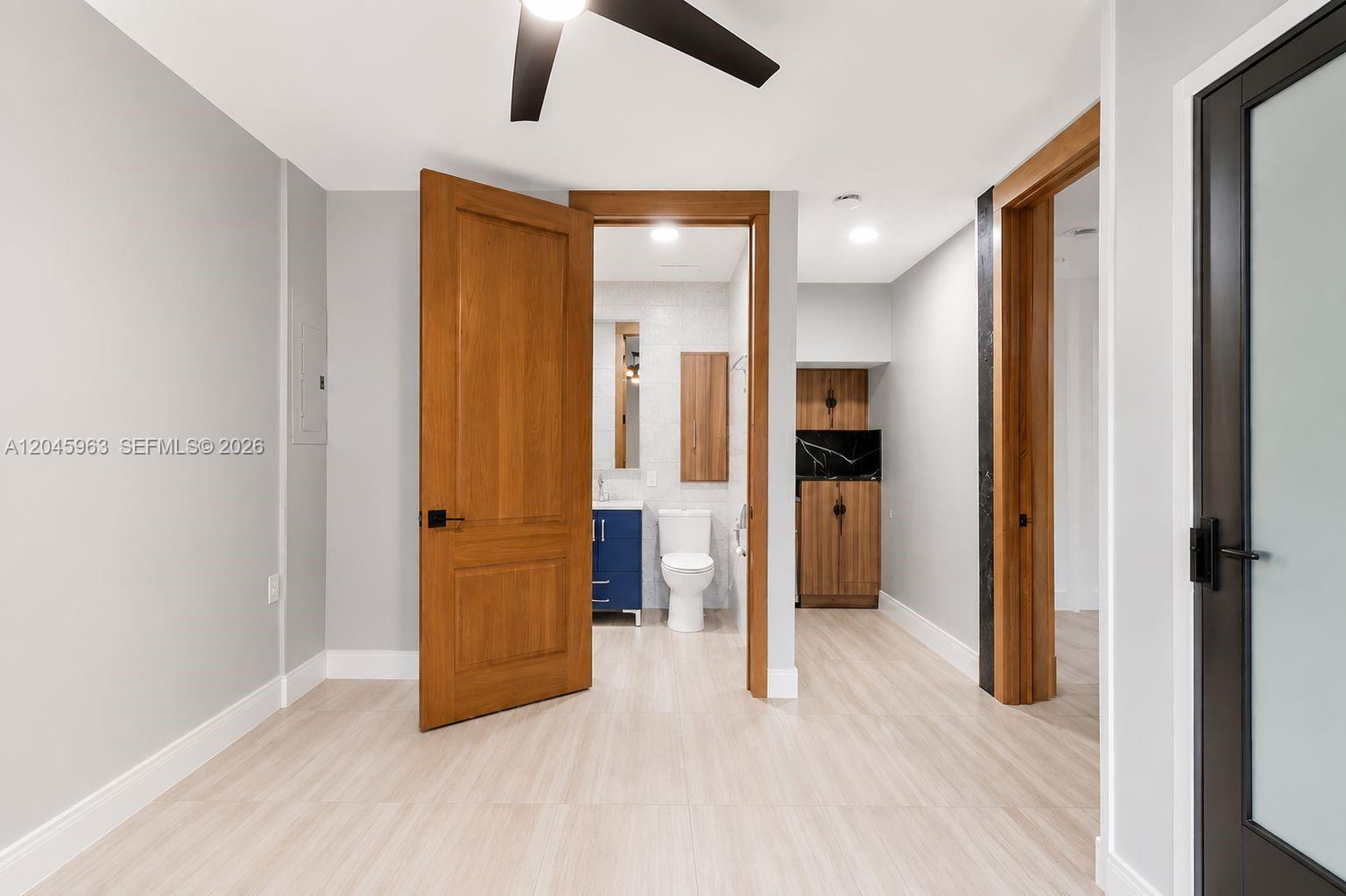 A room features light-colored tile flooring, gray walls, and wooden doors leading to a bathroom — 14888 SW 140th St # 1, Miami FL 33196, MIAMI, FL