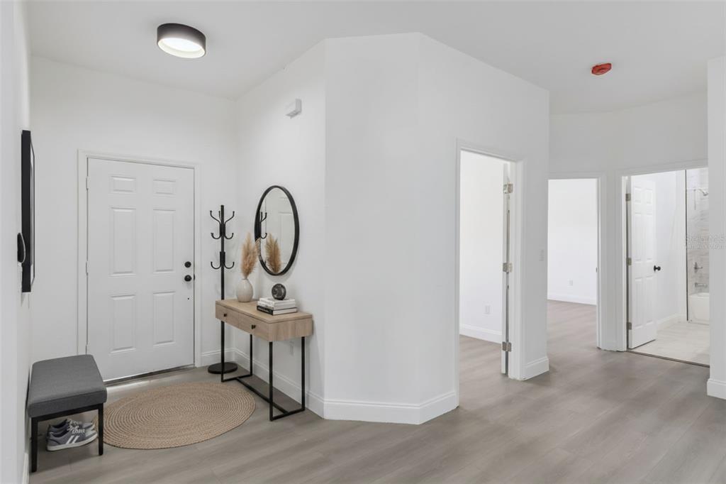 A bright entryway features white walls, light wood-look flooring, a console table, and a bench — 4436 WATERFORD DRIVE, LAKE WALES, FL