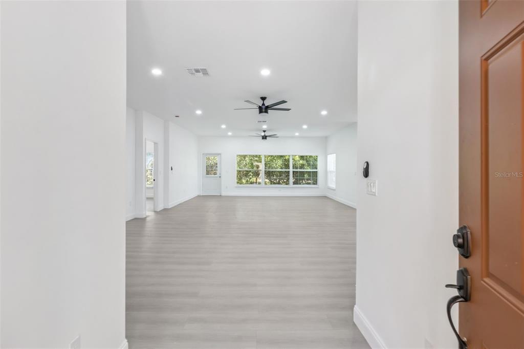 An interior view of a bright, open-concept living area with light wood-look flooring — 4436 WATERFORD DRIVE, LAKE WALES, FL