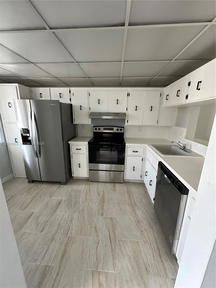 A kitchen features white cabinets, stainless steel appliances, and light-colored wood-look tile flooring — 3571 Inverrary Dr # 202, Lauderhill FL 33319, LAUDERHILL, FL
