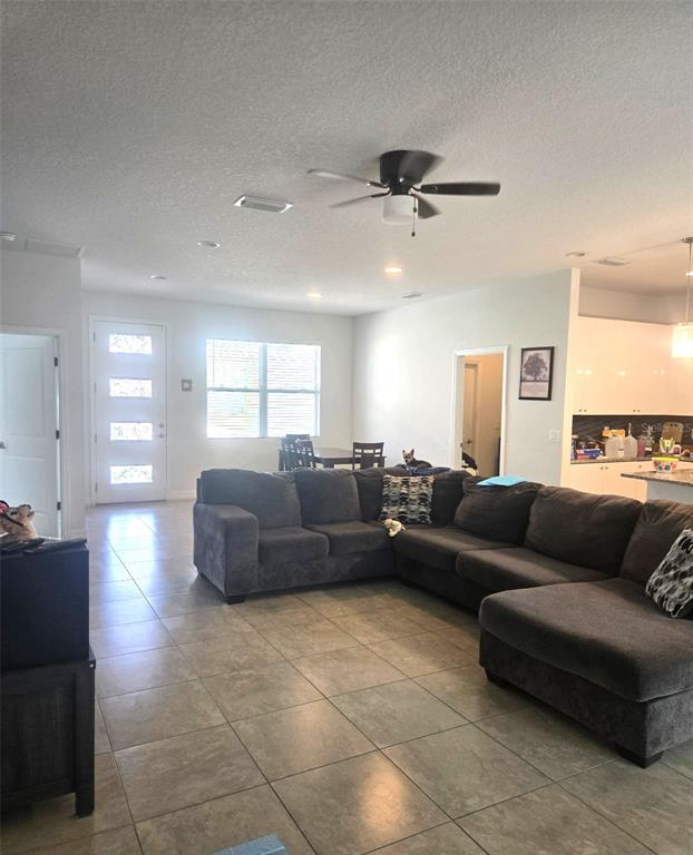 A living room with tile floors, a gray sectional sofa, and a ceiling fan — 40 ORCHID LANE, POINCIANA, FL
