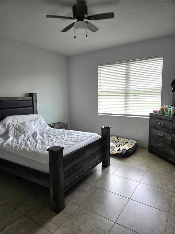 A bedroom features a dark wood bed frame, tiled floors, and a ceiling fan — 40 ORCHID LANE, POINCIANA, FL