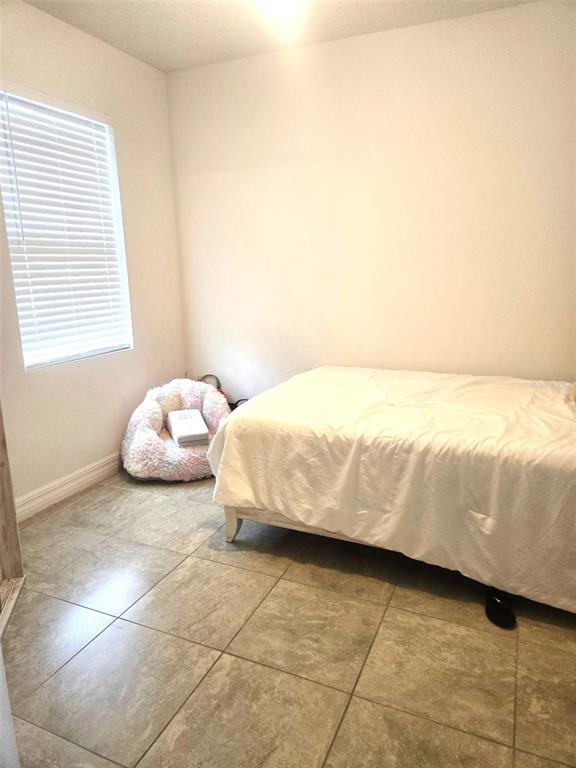 A bedroom with tiled floors, a bed with white bedding, and a window with blinds — 40 ORCHID LANE, POINCIANA, FL