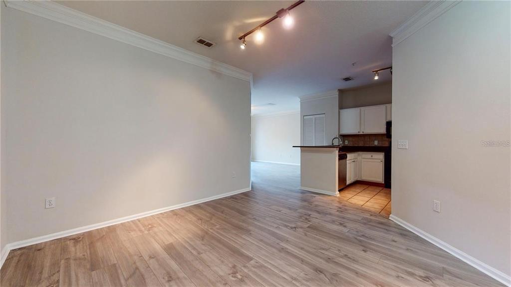 A dining area with wood-look flooring leads to a kitchen with white cabinets — 4207 S DALE MABRY HIGHWAY UNIT 3110, TAMPA, FL