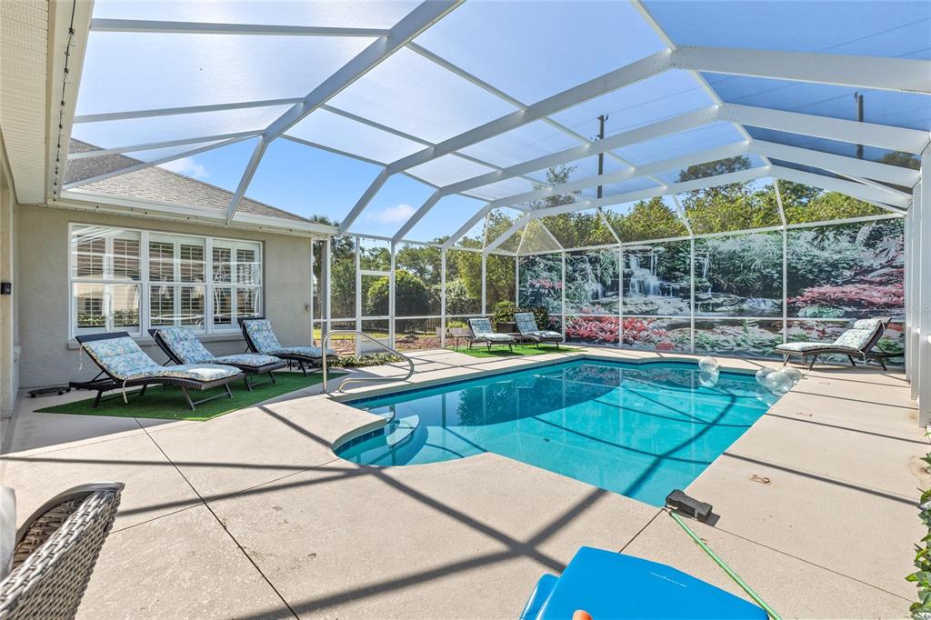 A screened-in swimming pool patio features lounge chairs on a concrete deck and artificial turf — 13932 SE 96TH CIRCLE, SUMMERFIELD, FL