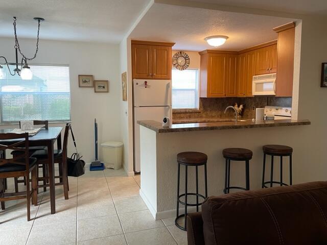 A kitchen with wood cabinets and a breakfast bar overlooks a dining area with tile floors — 348 Monaco H, Delray Beach FL 33446, DELRAY BEACH, FL