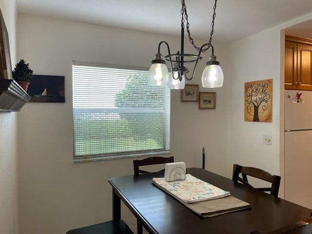 A dining area features a dark wood table, a chandelier, and a window with blinds — 348 Monaco H, Delray Beach FL 33446, DELRAY BEACH, FL