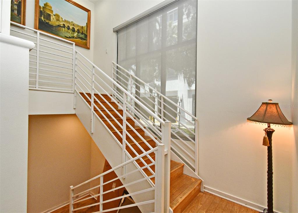 A staircase with white railings and wooden steps leads upward next to a large window — 460 E JACKSON STREET UNIT 5, ORLANDO, FL