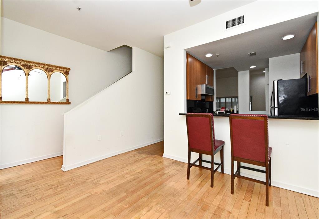 A kitchen with wood cabinets and a breakfast bar overlooks a room with hardwood floors — 460 E JACKSON STREET UNIT 5, ORLANDO, FL