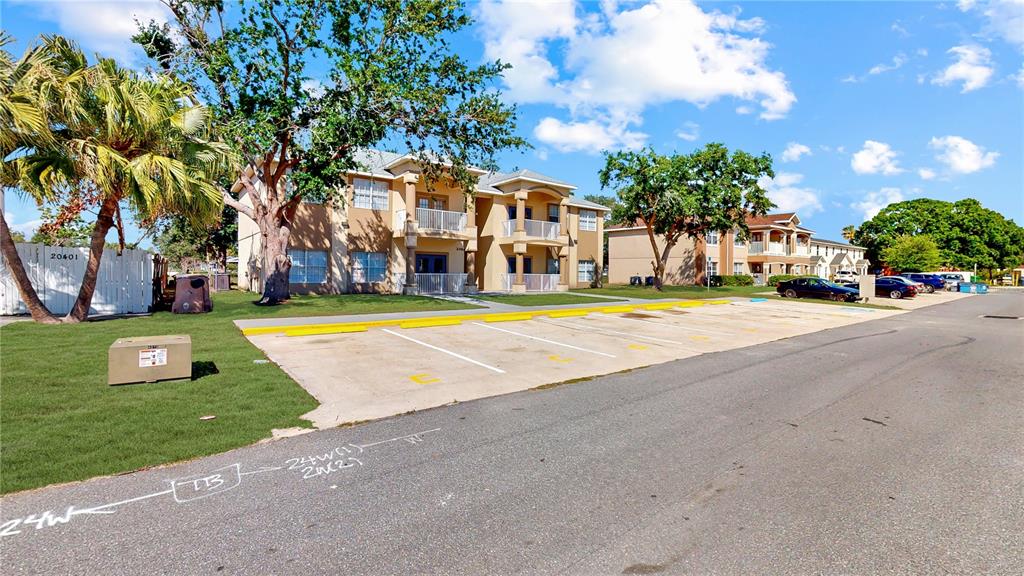 A multi-story apartment building features a paved parking lot in front with yellow painted curbs — 206 MAJORS LANE UNIT D, KISSIMMEE, FL