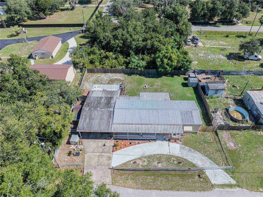 An aerial view shows a house with a metal roof, a driveway, and backyard structures — 3140 4TH STREET, DAVENPORT, FL