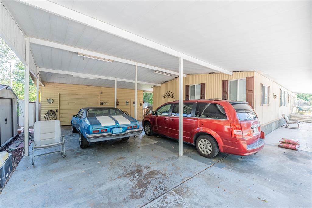 A covered carport features a concrete floor, a blue muscle car, and a red minivan — 3140 4TH STREET, DAVENPORT, FL