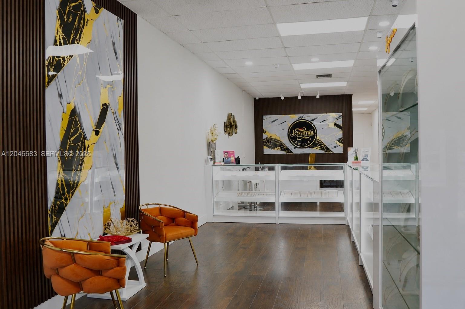 A jewelry store interior features orange chairs, glass display cases, and marble-patterned wall accents — 1341 N PALM AVE, Miramar FL 33024, MIRAMAR, FL