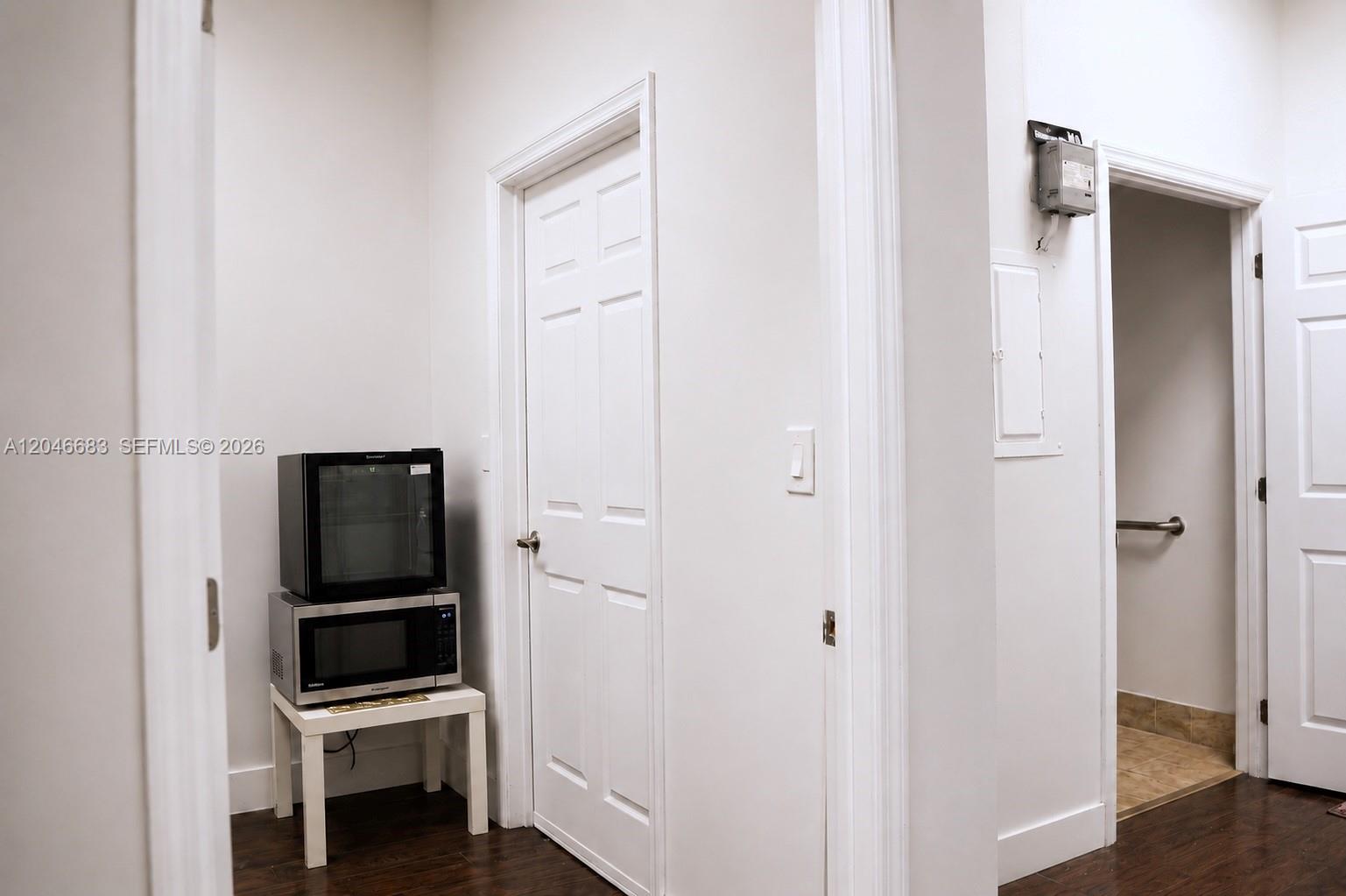 A small white table holds a microwave and mini-fridge in a hallway with two doors — 1341 N PALM AVE, Miramar FL 33024, MIRAMAR, FL