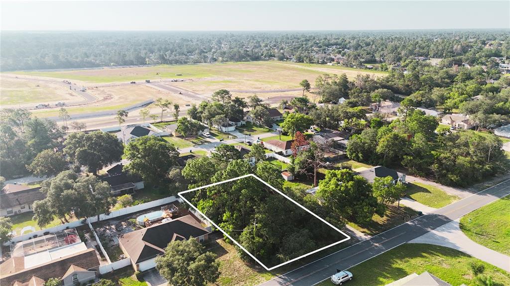 An aerial view shows a rectangular, tree-covered vacant lot outlined in white next to houses — 3581 LEMA DRIVE, SPRING HILL, FL