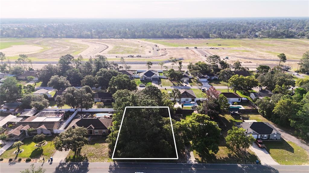 An aerial view shows a rectangular, tree-covered vacant lot situated between residential homes — 3581 LEMA DRIVE, SPRING HILL, FL