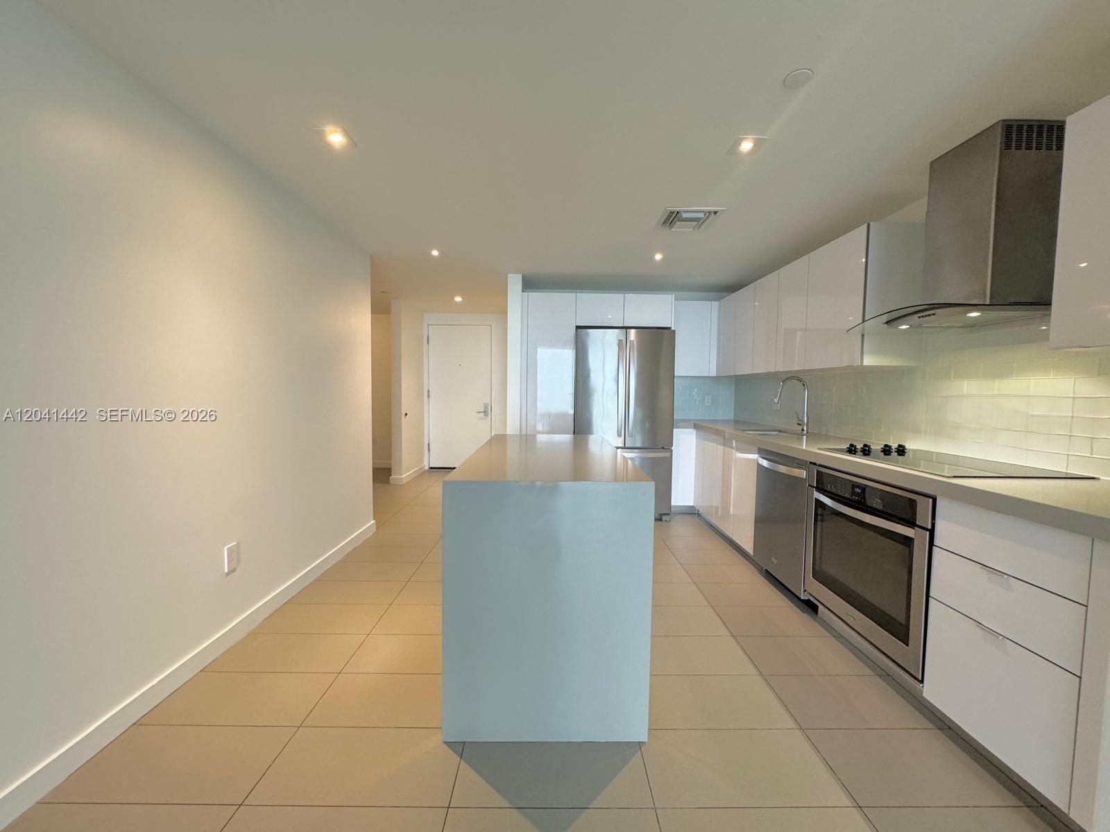 A modern kitchen features white cabinetry, stainless steel appliances, a central island, and tile flooring — 1600 NE 1st Ave # 3205, Miami FL 33132, MIAMI, FL