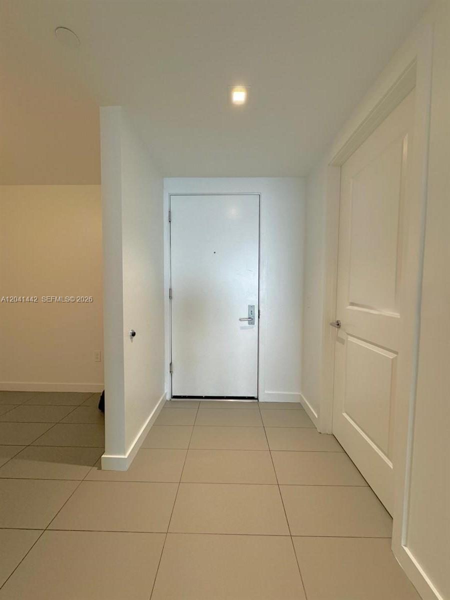 A white interior entryway features light-colored tile flooring and two closed doors — 1600 NE 1st Ave # 3205, Miami FL 33132, MIAMI, FL
