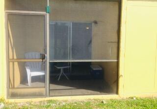 A screened-in patio features a white plastic chair, a small table, and a blue cooler — 1605 Meadows Circle W # 1605, Boynton Beach FL 33436, BOYNTON BEACH, FL