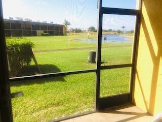 A view from a screened-in porch looking out onto a grassy lawn and a pond — 1605 Meadows Circle W # 1605, Boynton Beach FL 33436, BOYNTON BEACH, FL