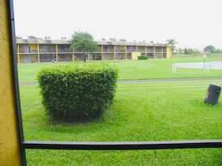 A view from a screened porch looking out at a grassy lawn and apartment building — 1605 Meadows Circle W # 1605, Boynton Beach FL 33436, BOYNTON BEACH, FL