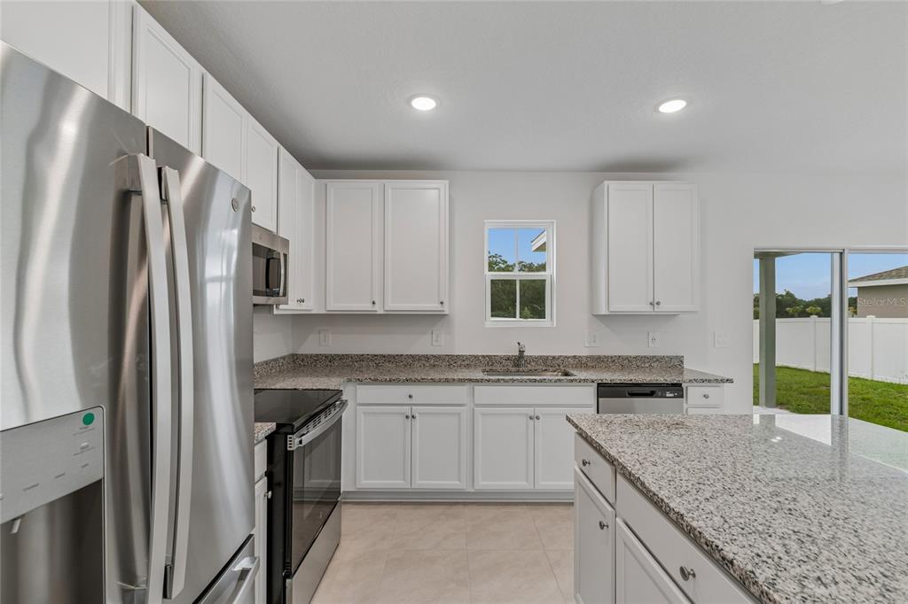 A kitchen features white cabinets, granite countertops, stainless steel appliances, and a center island — 3139 REIN AVENUE, DAVENPORT, FL
