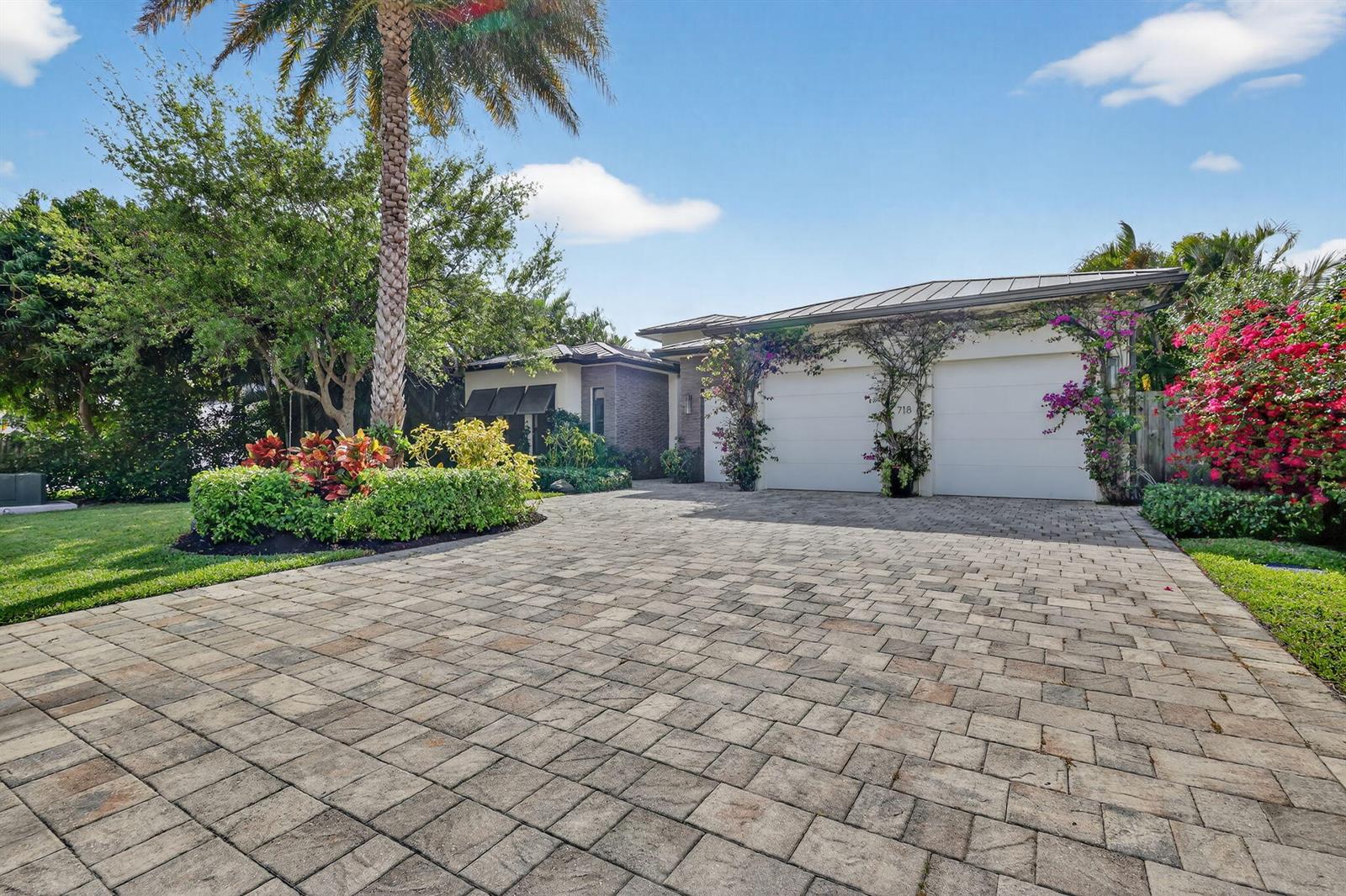 A paved driveway leads to a two-car garage of a house surrounded by lush landscaping — 718 NW 5th Avenue, Delray Beach FL 33444, DELRAY BEACH, FL