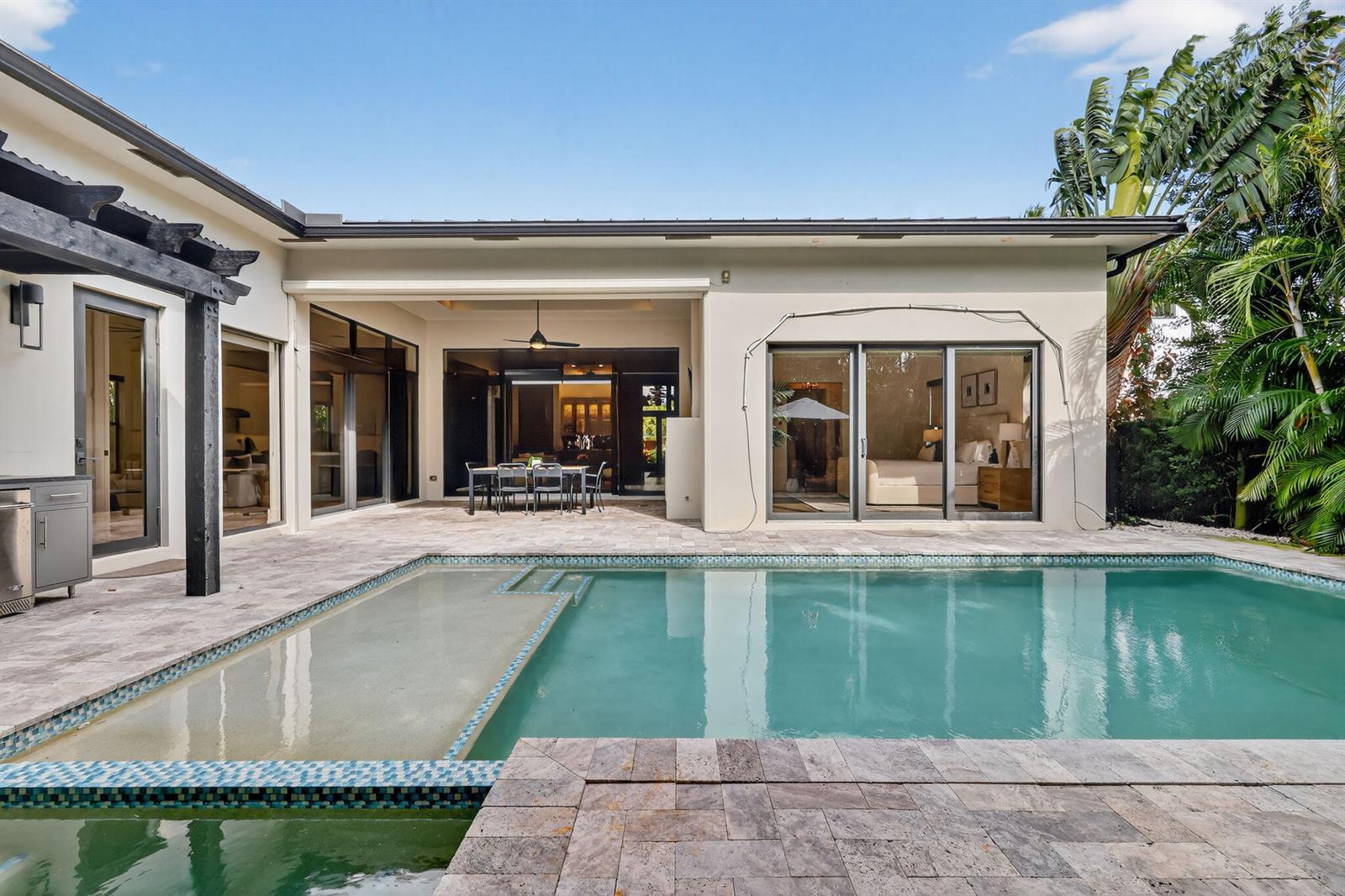 A patio with a swimming pool and outdoor dining area sits behind a modern house — 718 NW 5th Avenue, Delray Beach FL 33444, DELRAY BEACH, FL