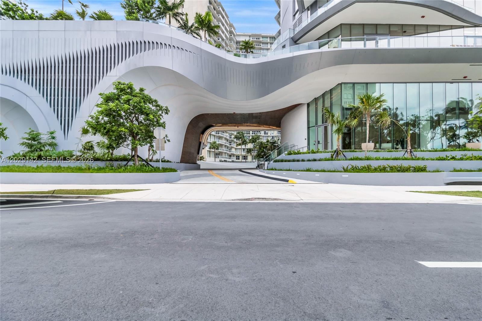 A modern building entrance features a curved white facade and a covered driveway — 175 SE 25 Rd # 1103, Miami FL 33129, MIAMI, FL