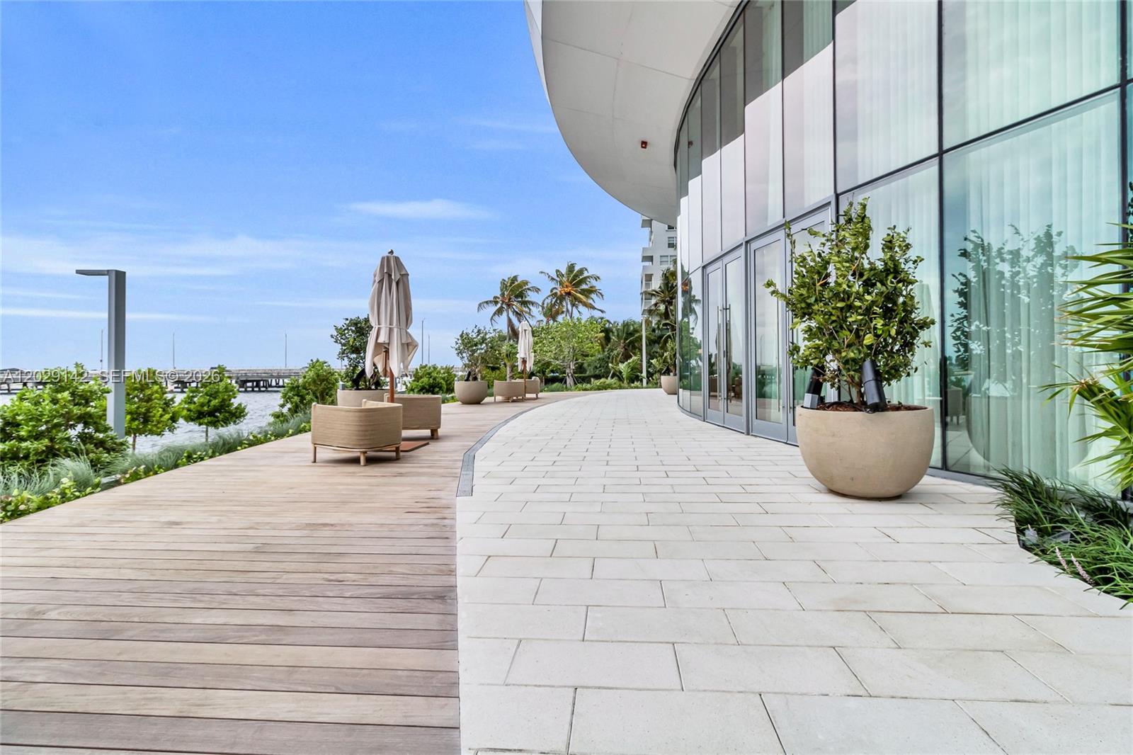 A modern outdoor patio features a wooden deck, stone pavers, and large potted plants — 175 SE 25 Rd # 1103, Miami FL 33129, MIAMI, FL