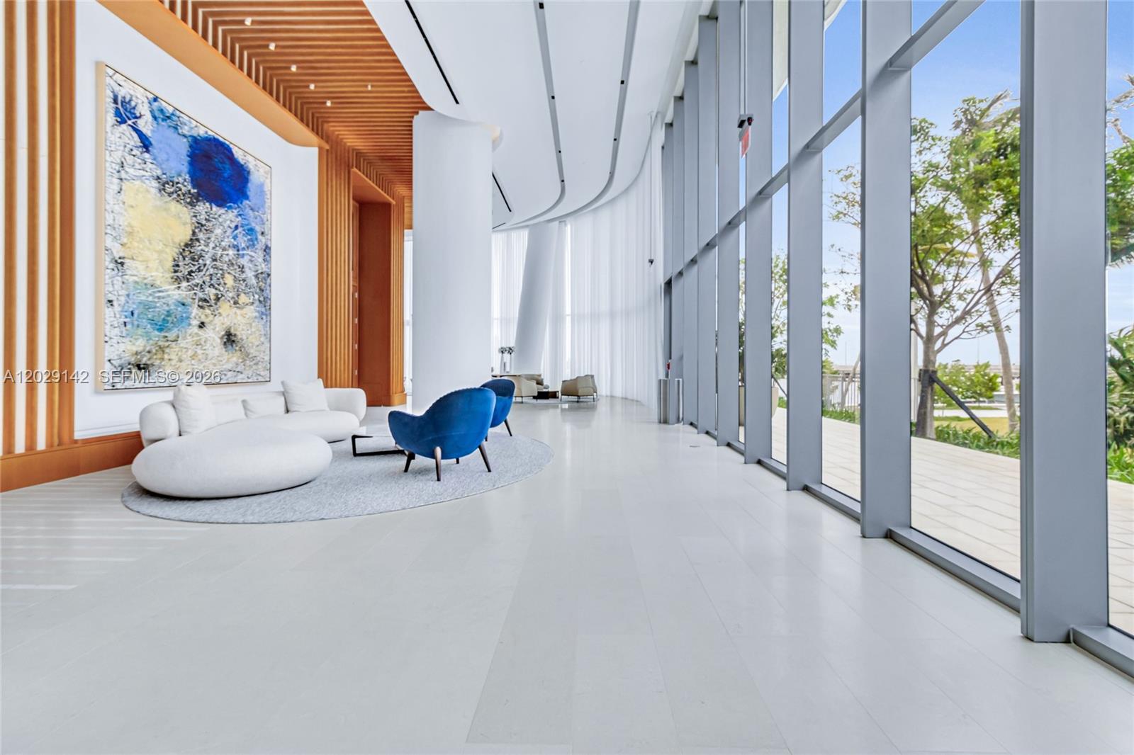 A modern lobby features white tile floors, blue accent chairs, and floor-to-ceiling glass windows — 175 SE 25 Rd # 1103, Miami FL 33129, MIAMI, FL