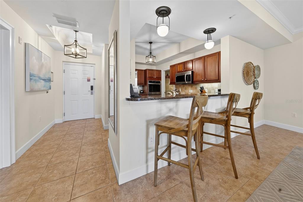A kitchen with wooden cabinets and a breakfast bar overlooks a tiled entryway — 102 YACHT HARBOR DRIVE UNIT 365, PALM COAST, FL