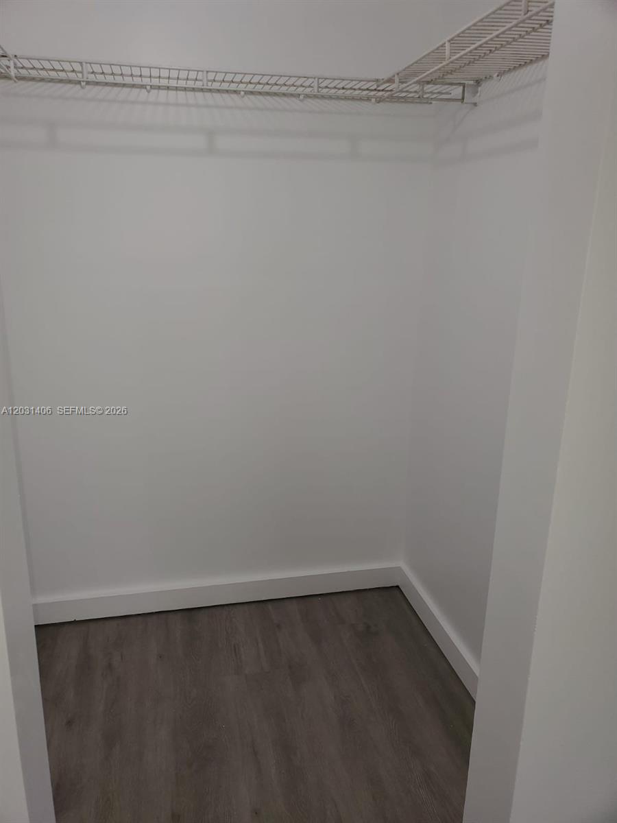 A small walk-in closet features white walls, gray wood-look flooring, and wire shelving — 750 NE 64th St # B511, Miami FL 33138, MIAMI, FL