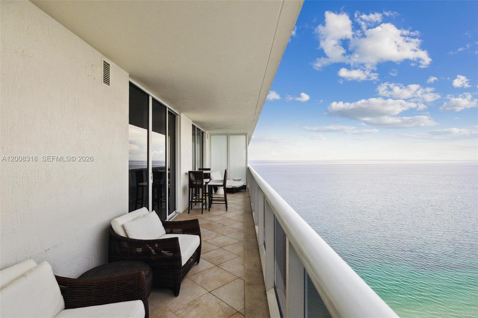 A balcony with outdoor furniture overlooks the ocean under a blue sky — 1830 S OCEAN DR # 4803, Hallandale Beach FL 33009, HALLANDALE BEACH, FL