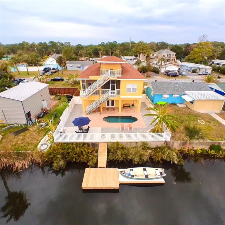 An aerial view shows a yellow three-story house with a pool, deck, and private dock — 7322 SHEEPSHEAD DRIVE, HUDSON, FL