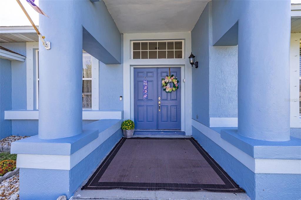 A blue house features a covered entryway with double doors and large support columns — 2931 PADDINGTON WAY, KISSIMMEE, FL