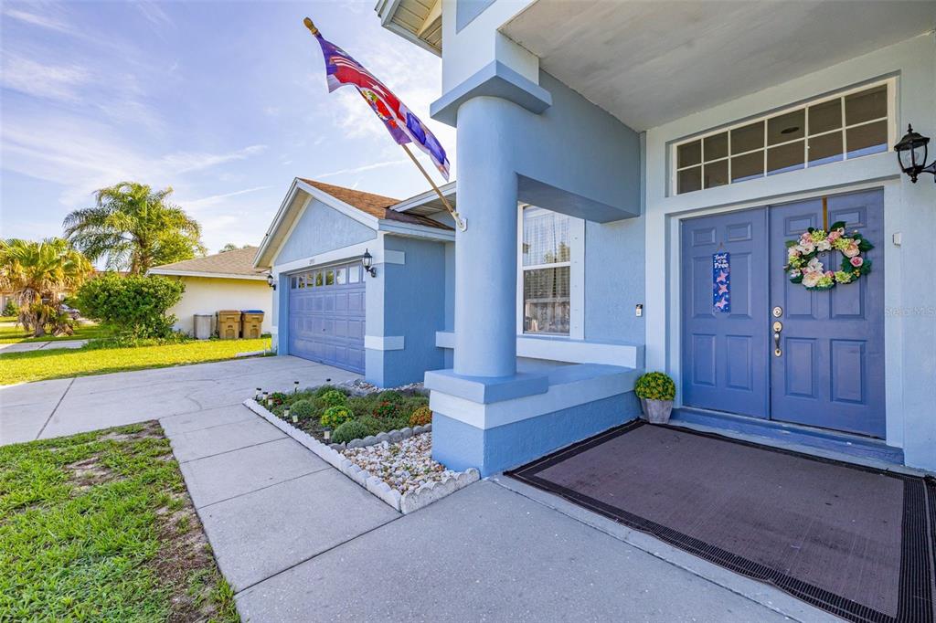 A blue house exterior features a double front door, a garage, and a concrete walkway — 2931 PADDINGTON WAY, KISSIMMEE, FL