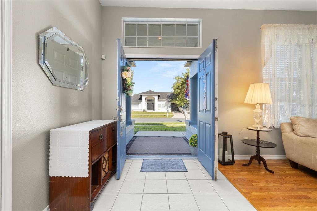 An entryway with tiled flooring opens through blue double doors to a view of houses — 2931 PADDINGTON WAY, KISSIMMEE, FL