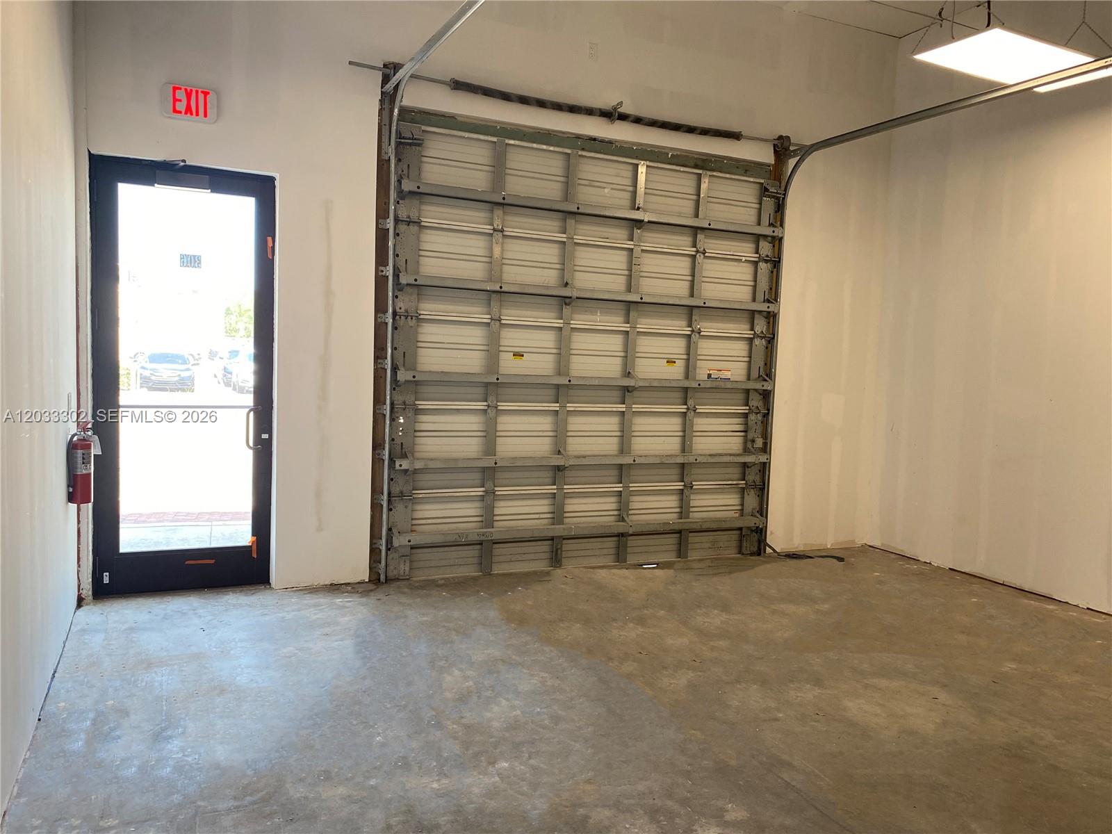 An interior view of a garage featuring a concrete floor, a roll-up door, and an exit — 300 SW 17th Ave # 4, Miami FL 33135, MIAMI, FL