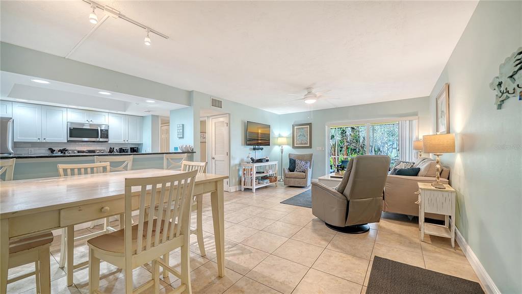 An open-concept living and dining area features tile flooring, light blue walls, and a kitchen — 5311 GULF OF MEXICO DRIVE UNIT 5, LONGBOAT KEY, FL