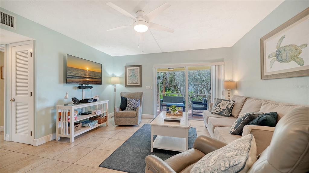 A living room features a beige sofa, armchair, white media console, and sliding glass doors — 5311 GULF OF MEXICO DRIVE UNIT 5, LONGBOAT KEY, FL