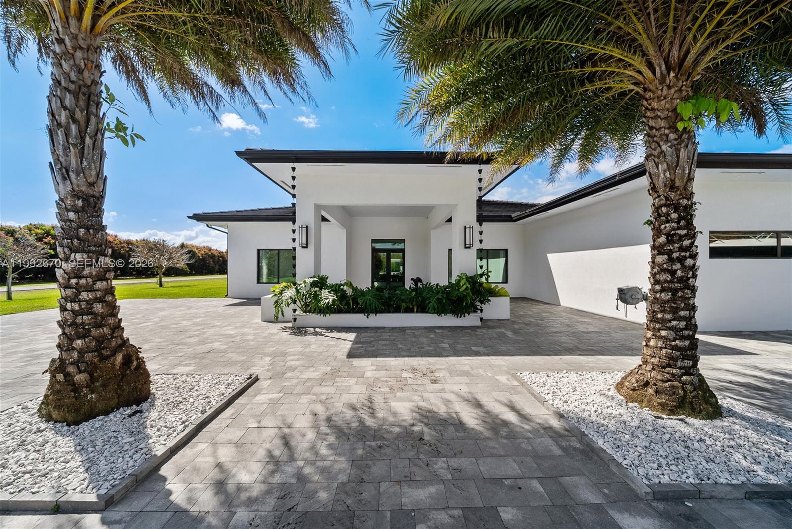 A modern white house features a paved driveway, two palm trees, and a central entryway — 17950 SW 192nd St, Miami FL 33187, MIAMI, FL