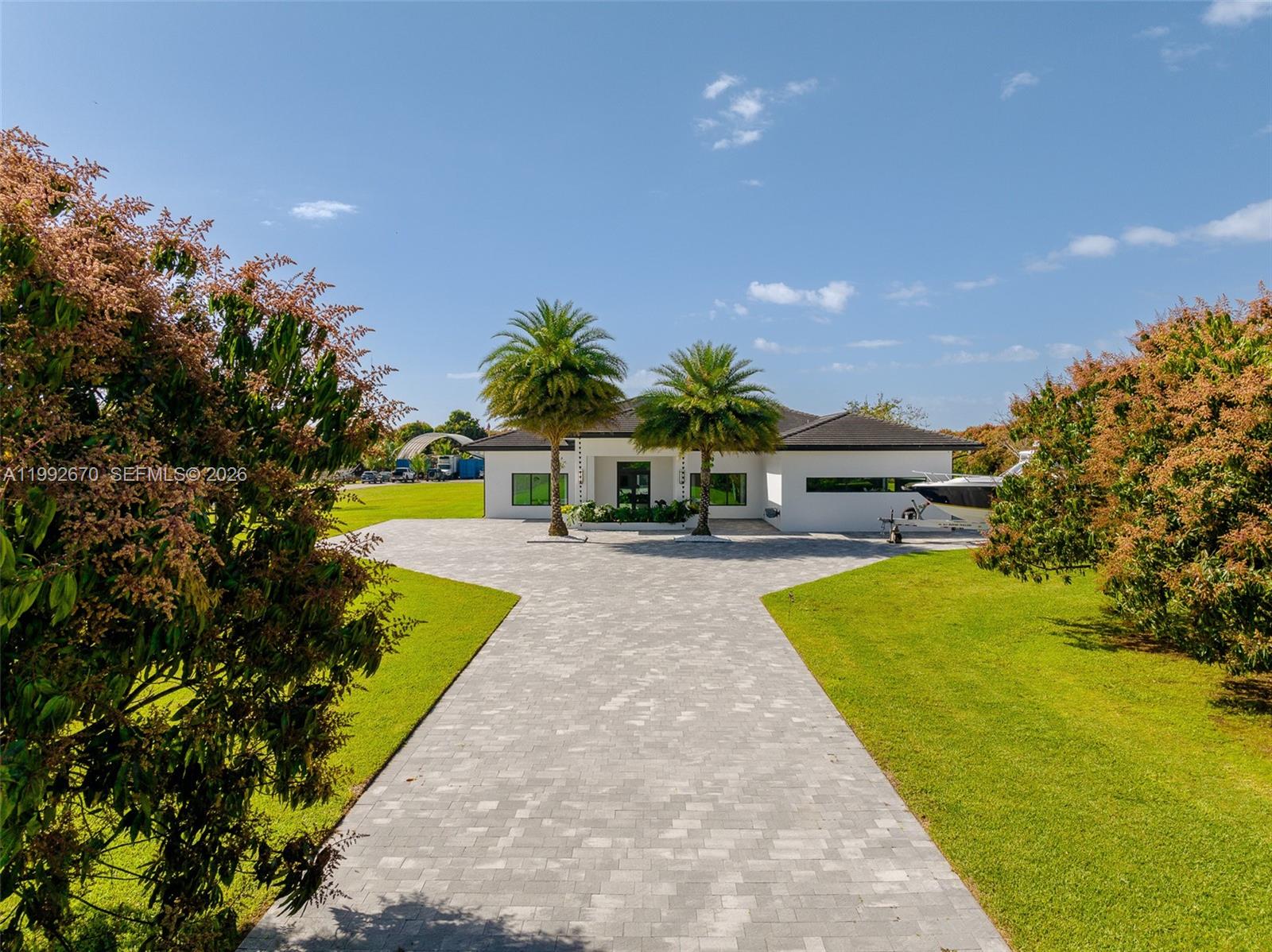 A white single-story house with a paved driveway and two palm trees in the front — 17950 SW 192nd St, Miami FL 33187, MIAMI, FL