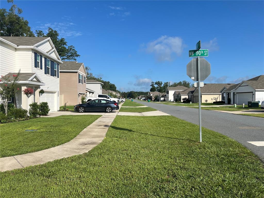 A suburban street features houses, a sidewalk, a stop sign, and a street sign — 19007 NW 164TH ROAD, HIGH SPRINGS, FL