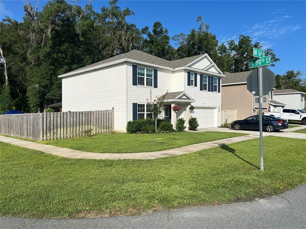A two-story house with white siding, blue shutters, and a fenced yard sits on a corner — 19007 NW 164TH ROAD, HIGH SPRINGS, FL