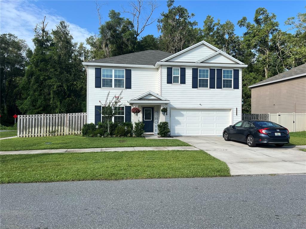A two-story white house with blue shutters and a two-car garage sits on a lawn — 19007 NW 164TH ROAD, HIGH SPRINGS, FL
