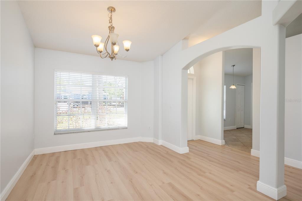 A dining room features light wood-look flooring, a chandelier, and an arched entryway — 1831 OAKGROVE AVENUE, DELTONA, FL