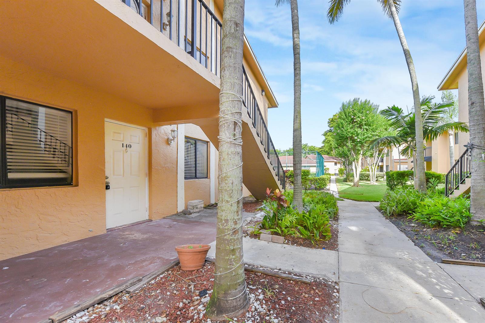 An exterior view of a two-story apartment building with a staircase and a walkway — 6053 10th 140 Avenue N # 140, FL 33463, FL