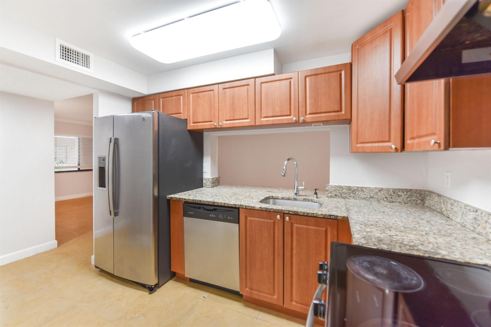 A kitchen features stainless steel appliances, wood cabinets, and granite countertops — 6053 10th 140 Avenue N # 140, FL 33463, FL
